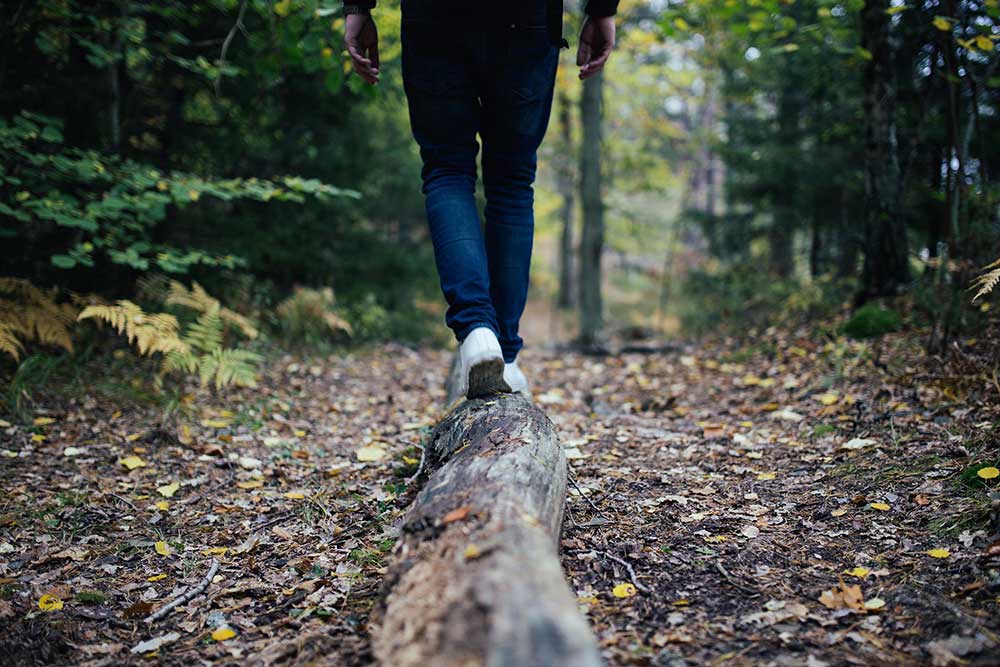 Guy walking on a log in the forest