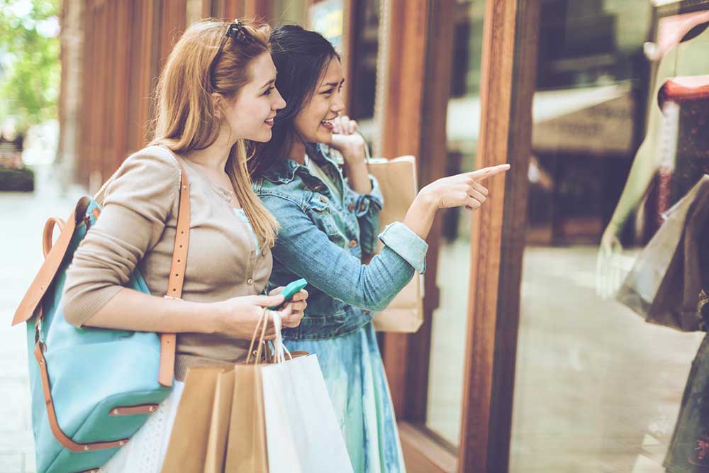 2 women with shopping bags window shopping